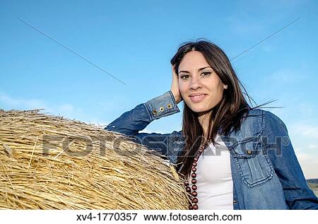 Brunette relaxing on bale in the countryside View Large Photo Image Stock Photo - Brunette relaxing on bale in the countryside. Fotosearch