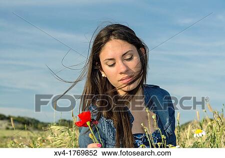 Stock Image - Brunette relaxing with poppy and enjoy in the countryside. Fotosearch