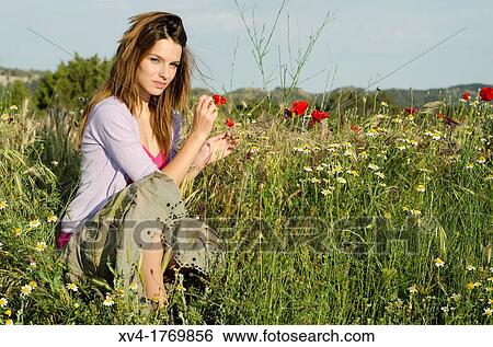 Stock Photograph - Brunette relaxing with poppy and enjoy in the countryside. Fotosearch