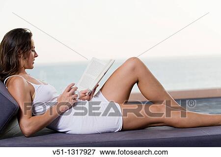 Brunette woman enjoying a book with a drink in a terrace with views at the sea View Large Photo Image Stock Photo - Brunette woman enjoying a book with a drink in a terrace with views at the sea. Fotosearch