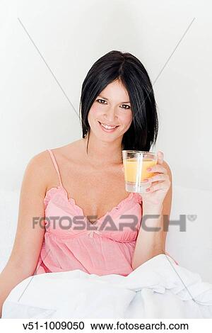 Stock Image - Brunette woman enjoying breakfast in bed. Fotosearch