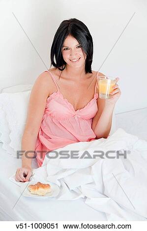 Brunette woman enjoying breakfast in bed View Large Photo Image Stock Image - Brunette woman enjoying breakfast in bed. Fotosearch