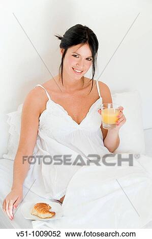 Brunette woman enjoying breakfast in bed View Large Photo Image Stock Image - Brunette woman enjoying breakfast in bed. Fotosearch