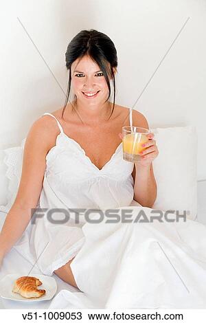 Brunette woman enjoying breakfast in bed View Large Photo Image Stock Image - Brunette woman enjoying breakfast in bed. Fotosearch