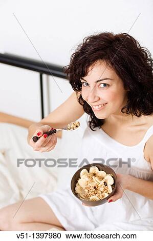 Stock Image - Brunette woman enjoying breakfast in bed. Fotosearch