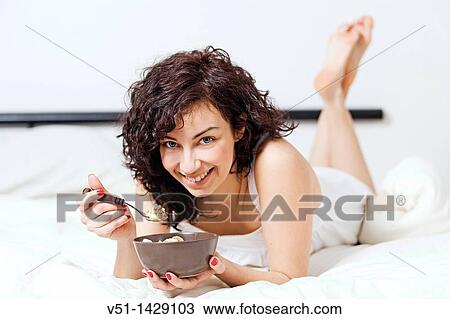 Brunette woman enjoying breakfast in bed View Large Photo Image Stock Image - Brunette woman enjoying breakfast in bed. Fotosearch