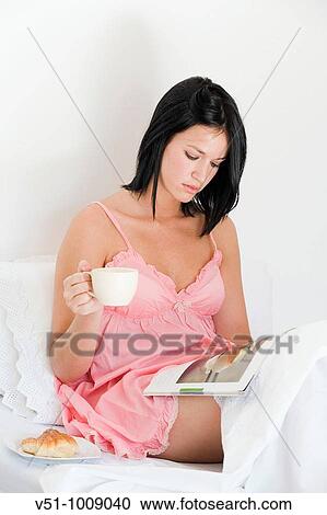 Brunette woman enjoying breakfast sitting in bed and reading a magazine View Large Photo Image Stock Image - Brunette woman enjoying breakfast sitting in bed and reading a magazine. Fotosearch