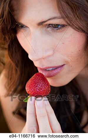 Brunette woman holding a strawberry to her lips. View Large Photo Image Stock Photograph - Brunette woman holding a strawberry to her lips.. Fotosearch