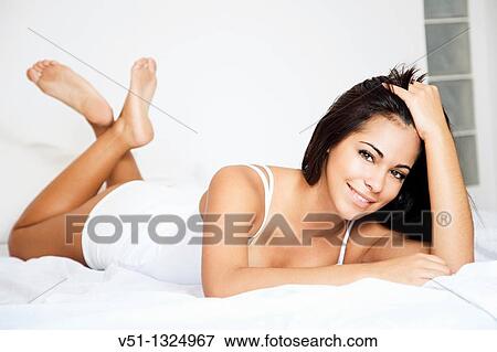 Stock Photo - Brunette woman lying down in bed. Fotosearch