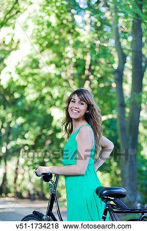 Brunette woman with bycicle in Park View Large Photo Image Stock Photo - Brunette woman with bycicle in Park. Fotosearch