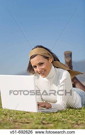 Brunette woman with laptop in the park View Large Photo Image Stock Photograph - Brunette woman with laptop in the park. Fotosearch