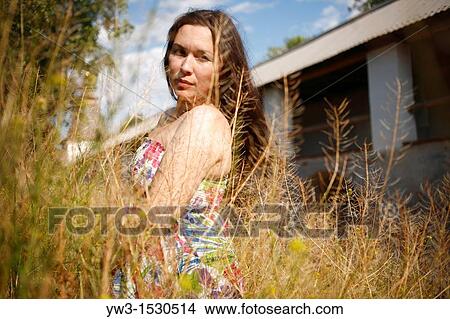 brunette women 25-30 years staying in the yellow grass against old gallery building View Large Photo Image Picture - brunette women 25-30 years staying in the yellow grass against old gallery building. Fotosearch