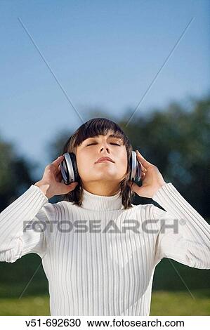 Brunette young woman enjoying music in the park View Large Photo Image Stock Image - Brunette young woman enjoying music in the park. Fotosearch