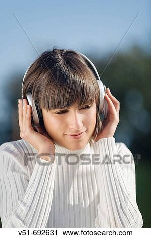 Brunette young woman enjoying music in the park View Large Photo Image Stock Image - Brunette young woman enjoying music in the park. Fotosearch