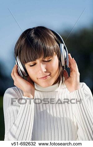 Brunette young woman enjoying music in the park View Large Photo Image Stock Image - Brunette young woman enjoying music in the park. Fotosearch