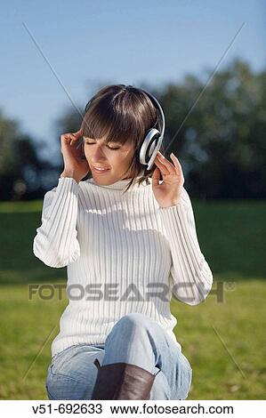 Brunette young woman enjoying music in the park View Large Photo Image Stock Image - Brunette young woman enjoying music in the park. Fotosearch