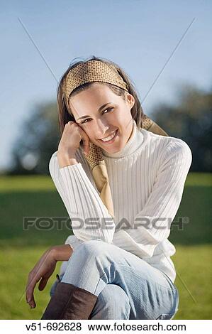 Brunette young woman smiling and sitting on the park bench View Large Photo Image Stock Photo - Brunette young woman smiling and sitting on the park bench. Fotosearch