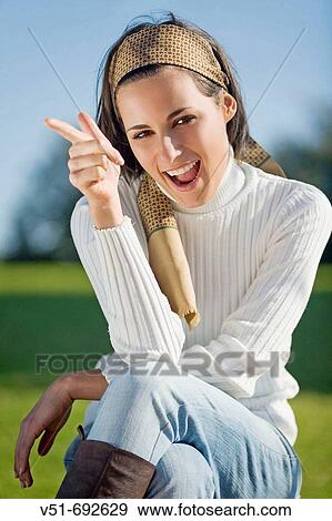 Stock Photo - Brunette young woman smiling and sitting on the park bench. Fotosearch