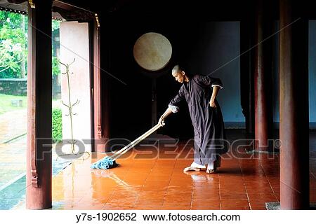Stock Image - Buddhist monk sweeping the floor of pagoda in Hue, Central Vietnam, Vietnam, Southeast Asia, Asia. Fotosearch