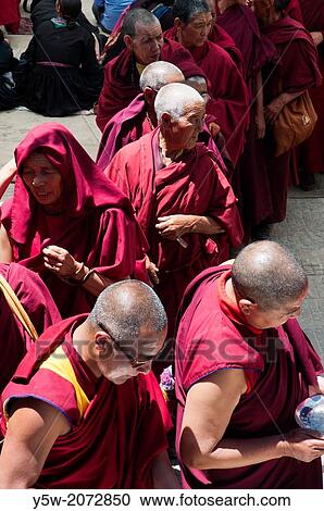 Stock Image - Buddhist monks line up for lunch in Leh, Ladakh, India. Many were visiting the town to celebrate the visit of their spiritual leader the Dalai Lama.. Fotosearch