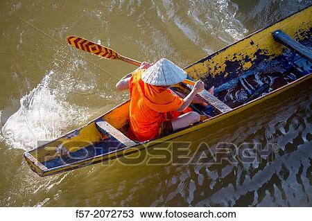 Stock Image - Buddhist monks on a row boat on the Mekong River in Paske, Laos.. Fotosearch