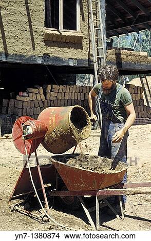 Builder of a mud brick house at work at his concrete mixer and wheelbarrow View Large Photo Image Picture - Builder of a mud brick house at work at his concrete mixer and wheelbarrow. Fotosearch