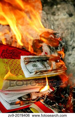Stock Photograph - Burning Lucky Money - Joss paper also known as ghost money are sheets of paper that are burned in traditional Chinese deity or ancestor worship ceremonies during special holidays.. Fotosearch