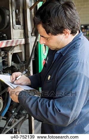 Bus Mechanic writng part numbers View Large Photo Image Stock Photo - Bus Mechanic writng part numbers. Fotosearch