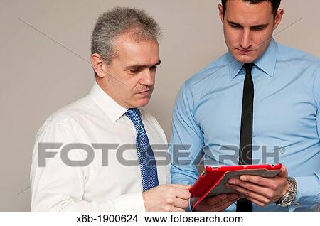 Picture - Business colleagues, one young and one older, discuss work using tablet computer. Fotosearch