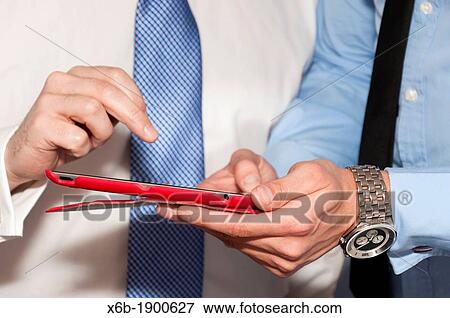 Business colleagues, one young and one older, discuss work using tablet computer View Large Photo Image Stock Photo - Business colleagues, one young and one older, discuss work using tablet computer. Fotosearch