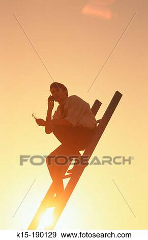 Business executive sitting on corporate ladder against setting sun View Large Photo Image Stock Photo - Business executive sitting on corporate ladder against setting sun. Fotosearch