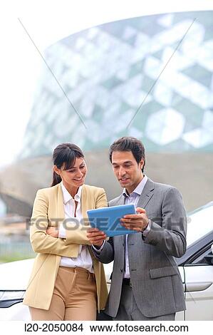 Picture - Business man and woman with tablet in parking business center. San Sebastian Technology Park. Donostia. Gipuzkoa. Basque Country. Spain.. Fotosearch