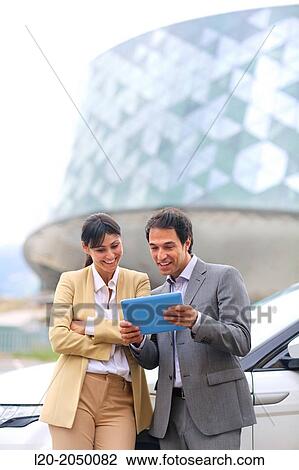 Stock Image - Business man and woman with tablet in parking business center. San Sebastian Technology Park. Donostia. Gipuzkoa. Basque Country. Spain.. Fotosearch