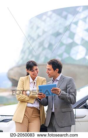 Stock Image - Business man and woman with tablet in parking business center. San Sebastian Technology Park. Donostia. Gipuzkoa. Basque Country. Spain.. Fotosearch