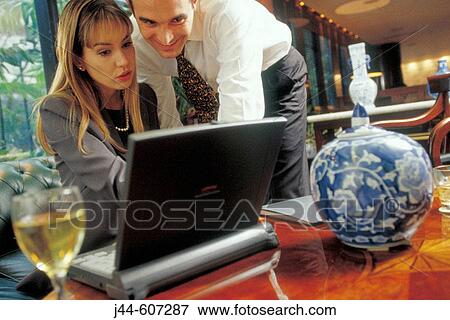 Business man and woman working with laptop in a hotel lounge View Large Photo Image Stock Photo - Business man and woman working with laptop in a hotel lounge. Fotosearch