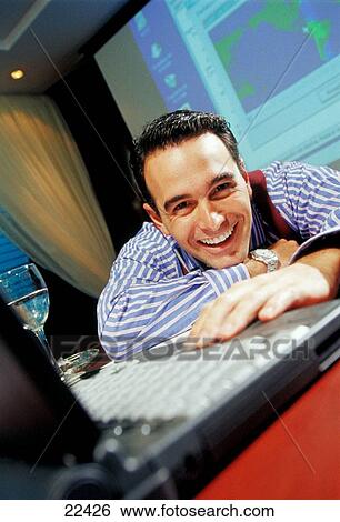 Stock Photograph - Business man laughing on desk with laptop computer. Fotosearch