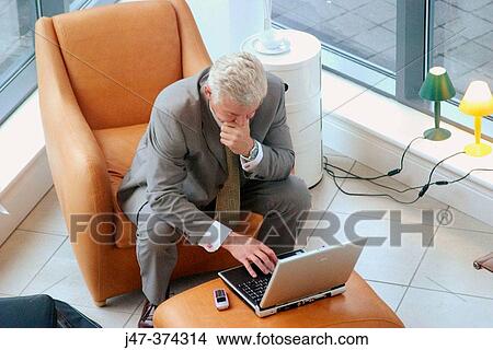 Business man sitting with laptop, concentrating on the screen View Large Photo Image Picture - Business man sitting with laptop, concentrating on the screen. Fotosearch