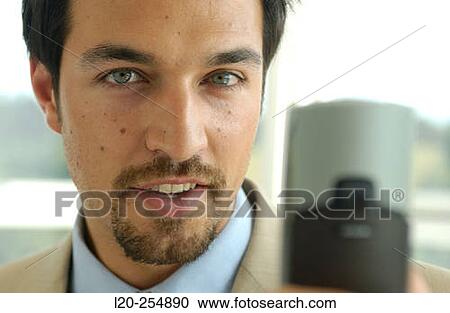 Business man using a cell phone equipped with a digital camera View Large Photo Image Stock Image - Business man using a cell phone equipped with a digital camera. Fotosearch