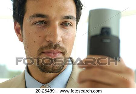 Business man using a cell phone equipped with a digital camera View Large Photo Image Stock Image - Business man using a cell phone equipped with a digital camera. Fotosearch