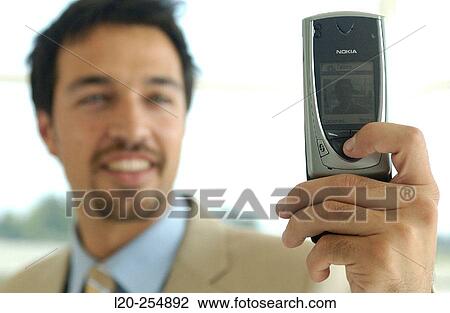 Business man using a cell phone equipped with a digital camera View Large Photo Image Stock Image - Business man using a cell phone equipped with a digital camera. Fotosearch