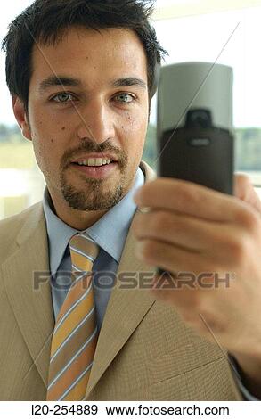 Business man using a cell phone equipped with a digital camera View Large Photo Image Stock Photo - Business man using a cell phone equipped with a digital camera. Fotosearch