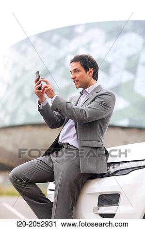 Stock Image - Business man with smartphone in parking business center. San Sebastian Technology Park. Donostia. Gipuzkoa. Basque Country. Spain.. Fotosearch