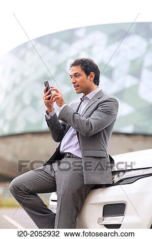 Stock Image - Business man with smartphone in parking business center. San Sebastian Technology Park. Donostia. Gipuzkoa. Basque Country. Spain.. Fotosearch