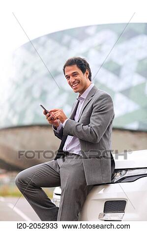 Stock Image - Business man with smartphone in parking business center. San Sebastian Technology Park. Donostia. Gipuzkoa. Basque Country. Spain.. Fotosearch