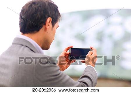 Stock Photography - Business man with smartphone in parking business center. San Sebastian Technology Park. Donostia. Gipuzkoa. Basque Country. Spain.. Fotosearch