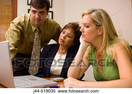 Business people looking at laptop computer in an office View Large Photo Image Stock Photography - Business people looking at laptop computer in an office. Fotosearch