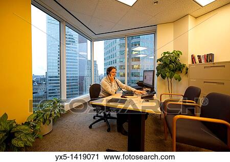 Business woman executive in a corner office sitting at the desk talking on the phone View Large Photo Image Stock Image - Business woman executive in a corner office sitting at the desk talking on the phone. Fotosearch