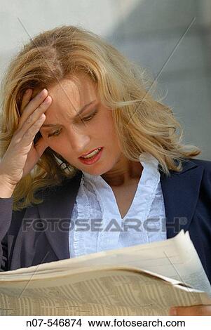 Picture - Business woman reading a newspaper and getting bad news.. Fotosearch