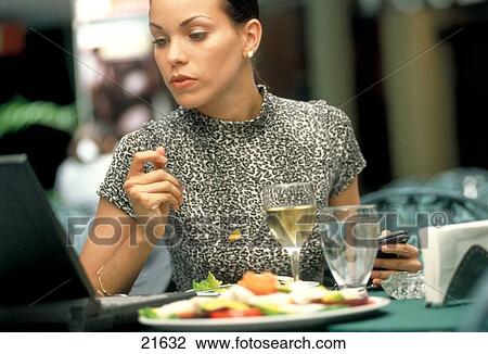 Business woman working with laptop while having lunch View Large Photo Image Stock Image - Business woman working with laptop while having lunch. Fotosearch