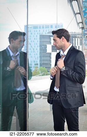 Businessman adjusting his tie in front of a mirror of a street. View Large Photo Image Stock Photo - Businessman adjusting his tie in front of a mirror of a street.. Fotosearch